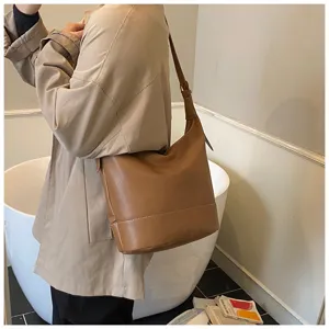 Brown leather bucket bag lifestyle detail shot showing retro style and exquisite stitching.