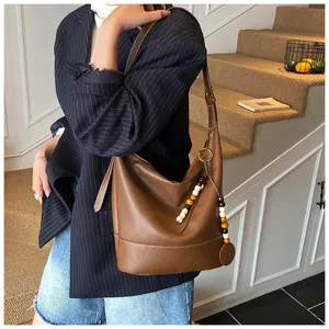Detailed view of the stylish brown retro leather shoulder bag with chic wooden bead charms.
