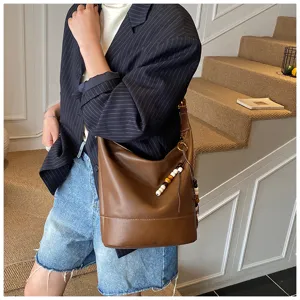 Detailed view of a vintage brown leather bucket shoulder bag with chic beaded charm.