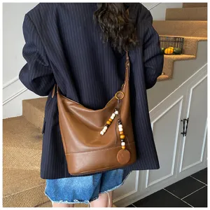 Detailed view of the stylish brown leather hobo bucket bag featuring a chic wooden bead pendant charm.