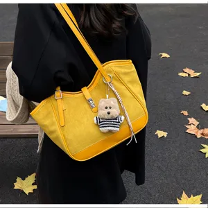 Vue détaillée du sac cabas d'épaule en suédine jaune rétro d'automne avec pendentif.