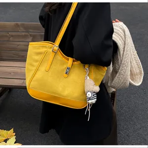 Vue détaillée d'un sac cabas élégant en suédine jaune avec joli pendentif, idéal pour l'automne.