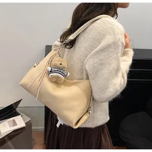 Detalle del bolso de hombro retro de ante con colgante de oso de peluche, estilo hobo.