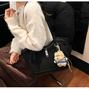 Détails du sac cabas noir avec pendentif ours, idéal pour le style et les déplacements.