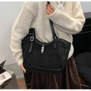 Vue de détail du sac cabas d'épaule en suédine noire avec serrure métallique et empiècement.