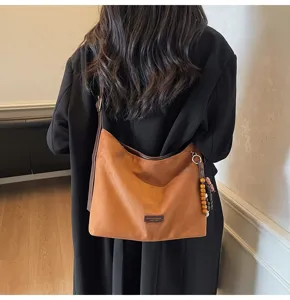 Vue détaillée du sac porté épaule marron en suédine rétro avec charmant pendentif en perles.