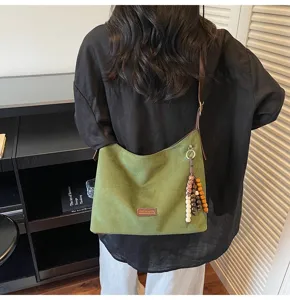 Vue détaillée du sac porté épaule rétro en suédine verte avec pendentif perlé chic.