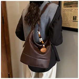 Detail shot showing the brown leather hobo shoulder bag worn on back with wooden bead charm.