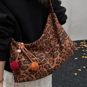 Leopard print slouchy shoulder bag for women, casual hobo tote with cute pom-pom pendants.