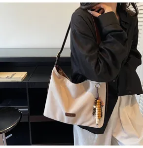 Vue détaillée d'un sac porté épaule vintage en daim avec lanière marron et charm de perles.