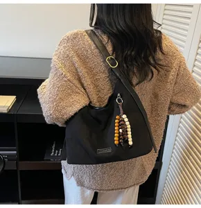 Détail de sac à bandoulière en suédine rétro décontracté, avec tissu noir et pampille en perles.