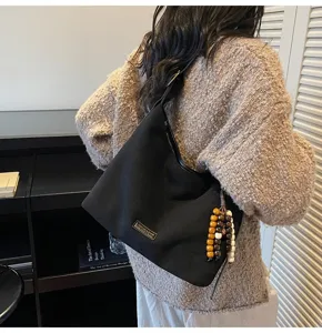 Vue détaillée du sac cabas d'épaule en suédine noire avec pendentif en perles, style chic.