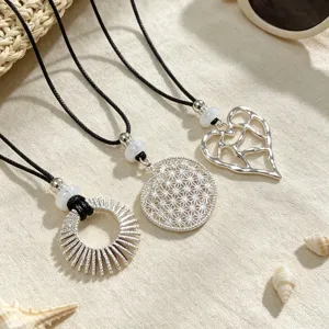 Detailed close-up of silver hollow sun ring, geometric disc, and heart pendant necklaces.