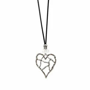 Detailed shot of silver hollow cracked heart pendant necklace with black cord and white bead.