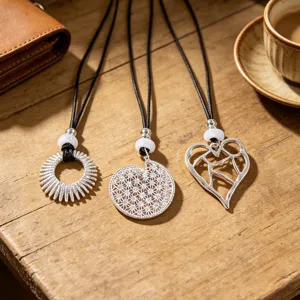 Close-up detail of silver hollow pendant necklaces on black cords, stylish sweater accessories.