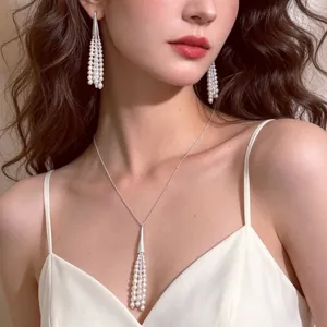 Close-up detail of elegant pearl tassel pendant necklace and matching earrings worn by model.