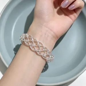 Primo piano di un braccialetto di perle di cristallo intrecciato argento su una mano chiara.
