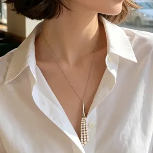 Elegant long pearl tassel pendant necklace featuring a sleek cone cap design. Detail shot.