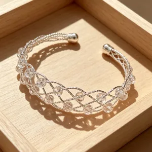 Bracciale rigido intrecciato color argento con perle di cristallo trasparente elegante.