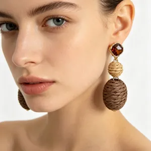 Close-up of ethnic vintage braided drop earrings featuring rhinestone and layered jute balls.