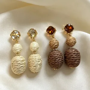 Closeup of vintage woven straw earrings with crystal studs, ethnic style boho jewelry detail.