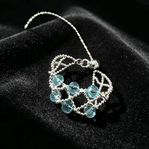 Detailansicht eines zarten, silbernen, verstellbaren Perlenrings mit hellblauen Kristallen.