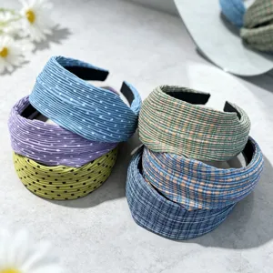 Detailed view of wide pleated headbands featuring polka dots and plaid patterns in various colors.