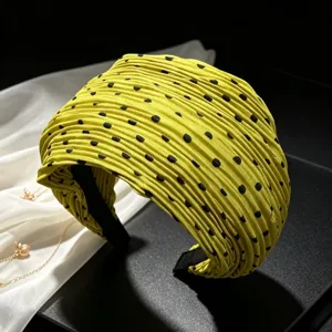 Detailed shot of yellow pleated polka dot wide headband, textured fabric fashion hair accessory.