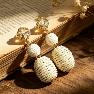 Close-up of vintage drop earrings featuring golden crystal studs and woven linen beads.