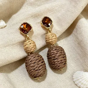 Detailed shot of retro woven raffia earrings with sparkling brown crystal and natural texture.