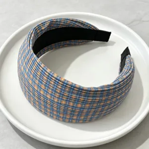Close-up of a wide pleated headband featuring a blue and orange plaid pattern for hair styling.