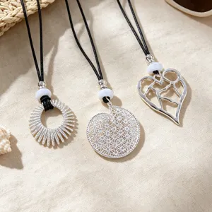 Silver hollow pendant necklace set, intricate metal design with black cord and white bead details.