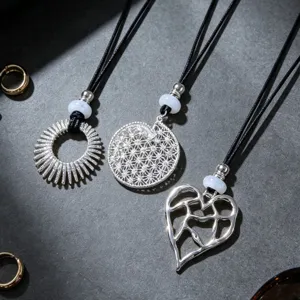 Detailed view of three silver pendant necklaces featuring sunburst, mandala, and heart designs.