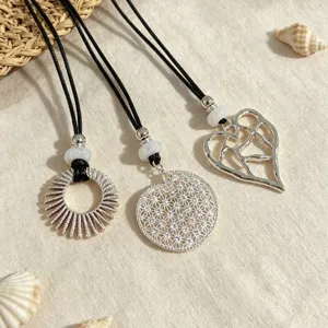 Silver openwork pendant necklace set featuring intricate hollow metal designs on black cords.