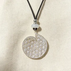 Detailed view of silver hollow geometric spiral pendant necklace with black cord and beads.