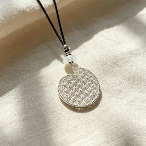 Detailed view of silver spiral shell pendant necklace with intricate four-leaf clover filigree.