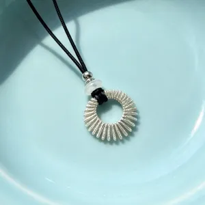 Silver sunburst ring pendant necklace with black cord, elegant minimalist jewelry accessory.