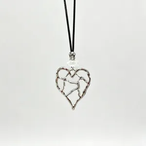 Detailed shot of a silver hollow heart pendant necklace with a black cord and white bead.