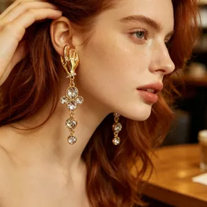 Close-up detail of vintage gold hand-shaped dangling earrings with sparkling rhinestones.