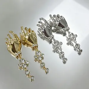 Detail view of vintage surrealist hand-shaped earrings with sparkling rhinestone tassels.
