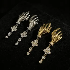 Detailed close-up shot of retro hand-shaped rhinestone tassel earrings in gold and silver.