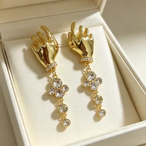 Detailed view of french vintage gold hand shaped dangle earrings with sparkling rhinestones.