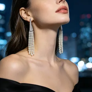 Close-up detail shot of long multi-strand pearl tassel earrings worn by model at night.