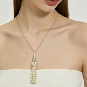 Close-up of a silver chain necklace featuring a cone pendant with multi-strand pearl tassels.