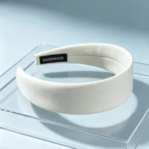 Detailed close-up view of a solid white wide fabric hair hoop displayed on stand.