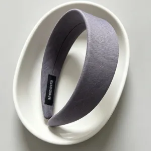 Detailed view of the wide fabric headband in grey, minimalist product photography setup.