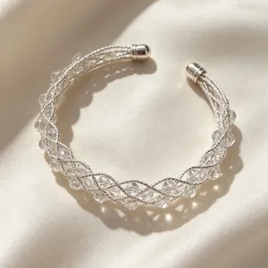 Primo piano dettagliato di un bracciale rigido in metallo intrecciato con perle di cristallo.