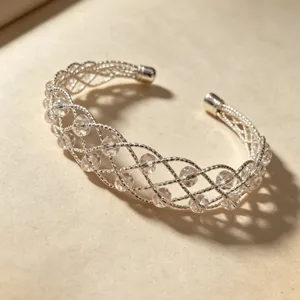 Primo piano dettagliato del bracciale rigido intrecciato in argento con perle di cristallo.