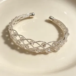 Bracciale rigido intrecciato argentato con perle di cristallo trasparente elegante.
