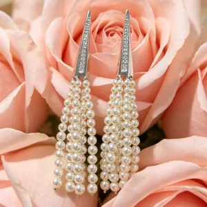 Detailed close-up view of chic cone shaped rhinestone encrusted multi strand pearl fringe earrings.